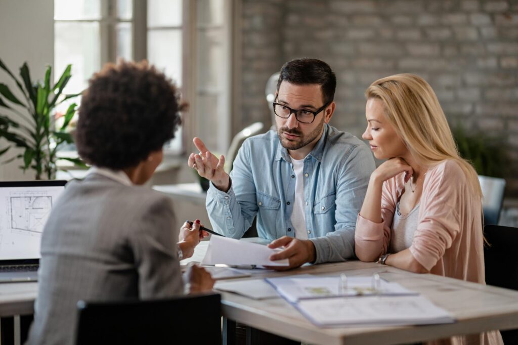 Couple échangeant avec une conseillère autour de documents de financement immobilier